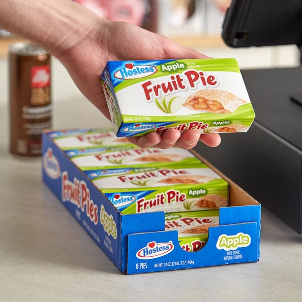 A hand holding a box of Hostess Apple Fruit Pies.