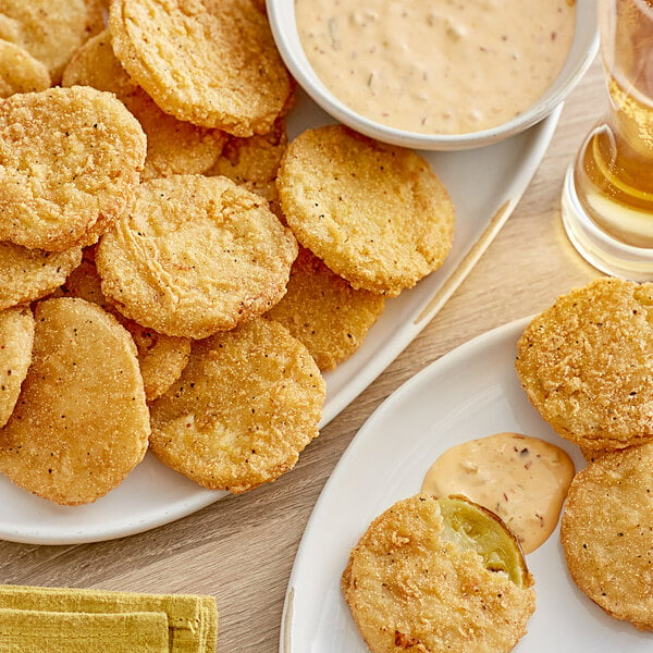 A plate of Harvest Creations Dipt'n Dusted fried green tomatoes with a bowl of dipping sauce.