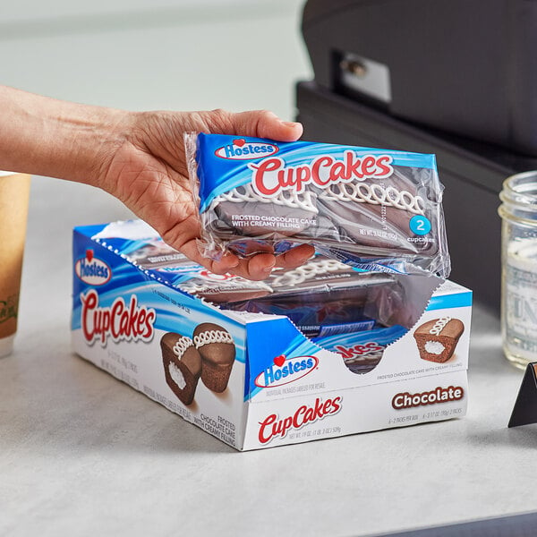 A hand holding a package of Hostess CupCakes.