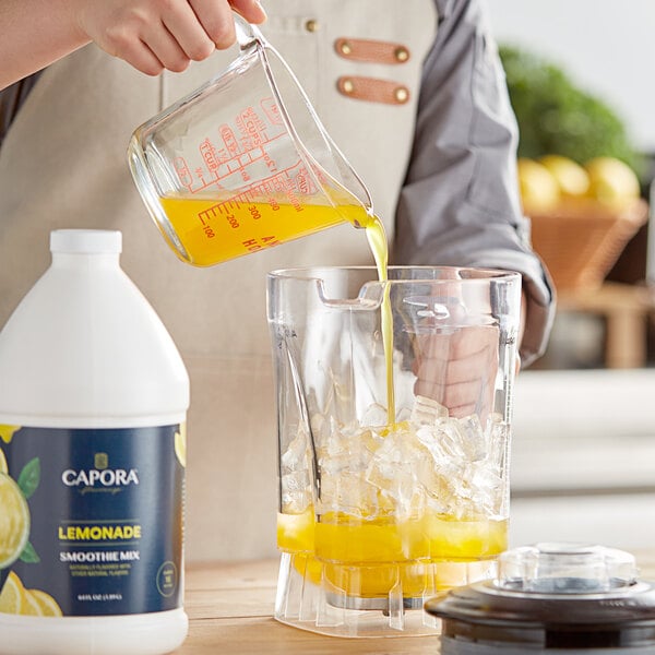 A person pouring Capora Lemonade Fruit Smoothie mix into a blender.