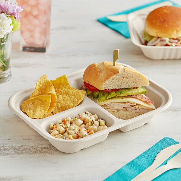 A World Centric 3-compartment compostable fiber container with a sandwich, chips, and a drink on a table.