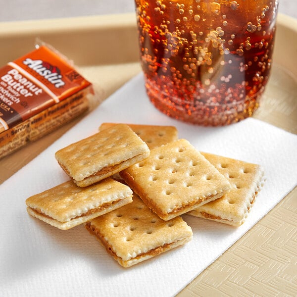 Austin Peanut Butter on Toasty Sandwich Crackers on a tray with a group of crackers on a napkin next to a glass of liquid.