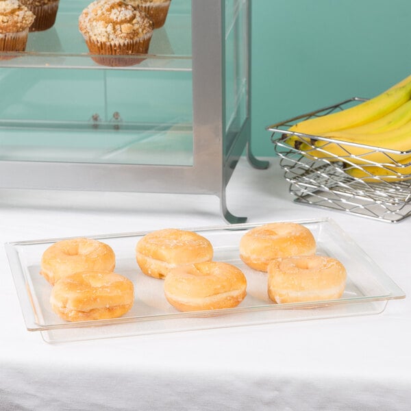 A Cal-Mil clear bakery tray with a variety of donuts on a table.