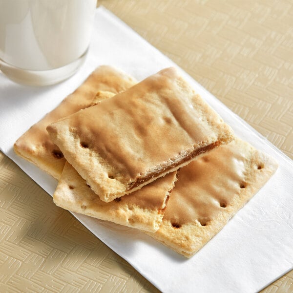 A stack of brown sugar cinnamon Pop-Tarts on a napkin next to a glass of milk.