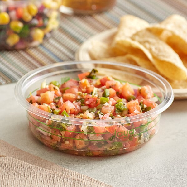 A bowl of salsa in a Stalk Market clear plastic deli container with chips.