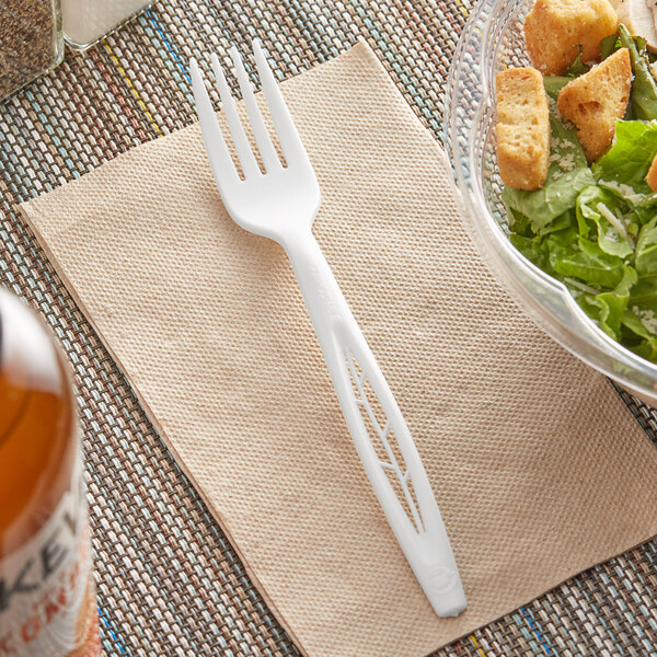 A clear bowl of salad with a Stalk Market white CPLA fork on a napkin.
