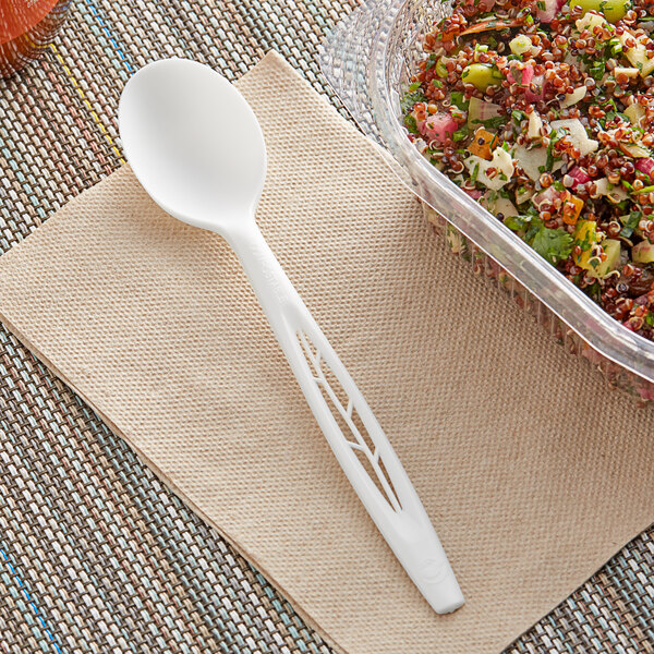 A white Stalk Market CPLA spoon on a napkin next to a bowl of food.