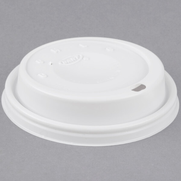 A white plastic lid with a hole on top of a coffee cup.