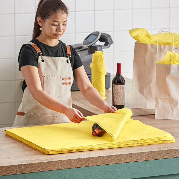 A woman in an apron cutting yellow Lavex tissue paper on a counter.