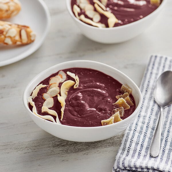 A bowl of red Acai with almonds and a spoon.