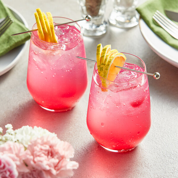 Two glasses of Perfect Puree Prickly Pear drinks with straws and lemon slices.