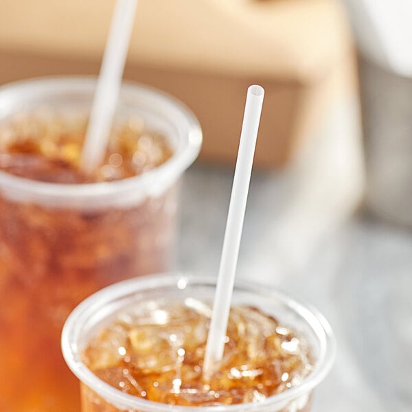 A close-up of a couple of plastic cups with Choice jumbo clear wrapped straws in them.