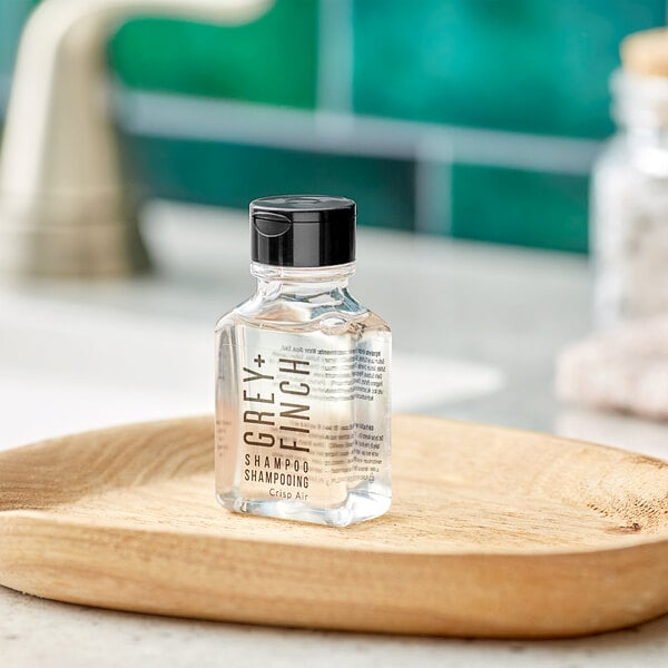 A close-up of a Grey + Finch bottle of shampoo on a wooden dish.