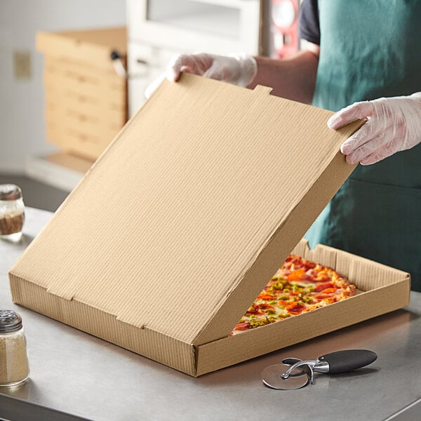 A person holding a Kraft cardboard pizza box with a pizza inside.