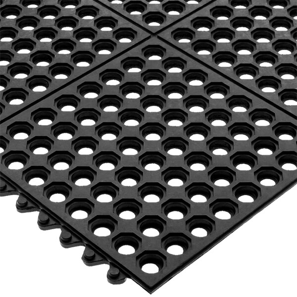 A black rubber San Jamar Connect-A-Mat with holes in it.