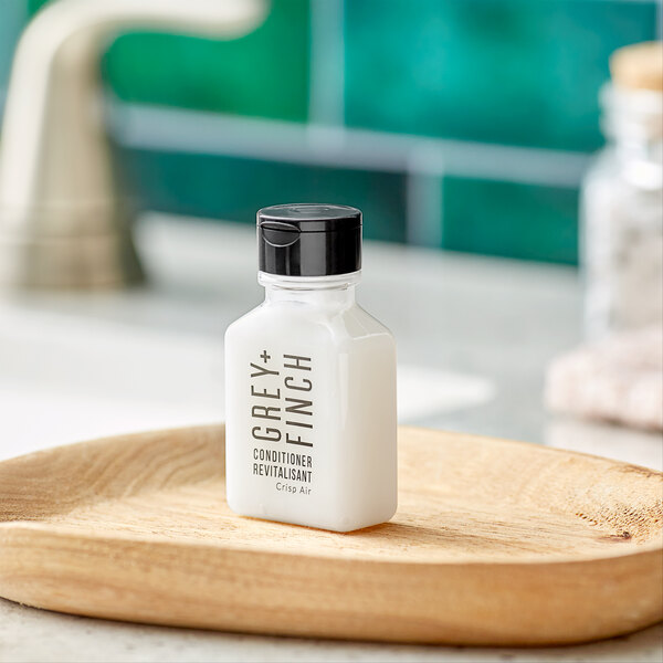 A case of Grey + Finch Crisp Air Conditioner bottles on a wooden hotel counter.