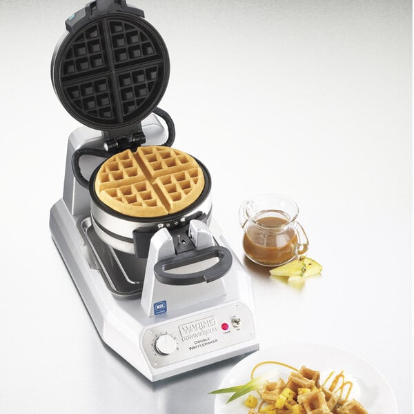 A Waring Double Belgian Waffle Maker with waffles on a plate and syrup.