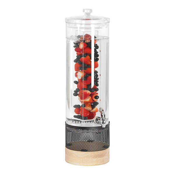 A Cal-Mil glass beverage dispenser with fruit inside on a white-washed wood and metal base.