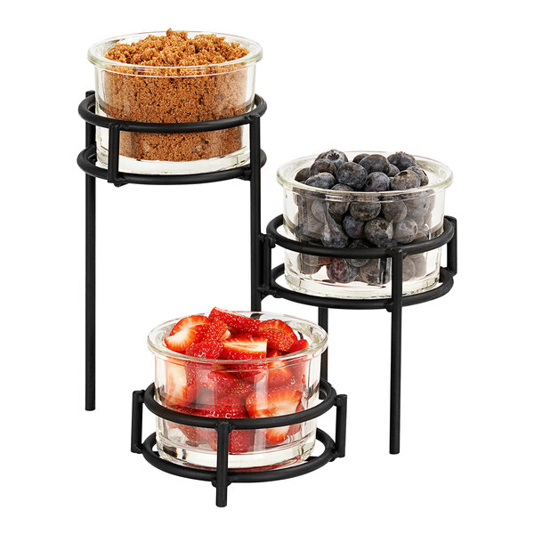 A Cal-Mil black 3-tier condiment display with three glass jars filled with strawberries, brown sugar, and fruit.