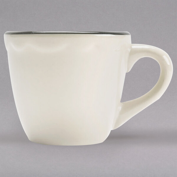 A white CAC china cup with a handle and a black scalloped edge.