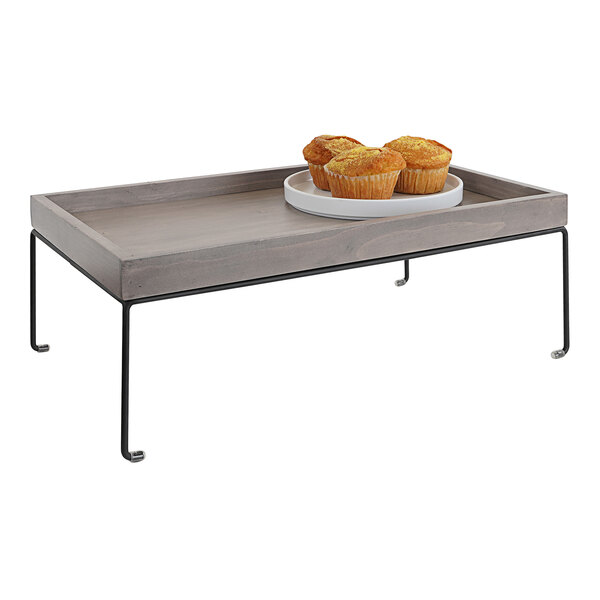 A Cal-Mil gray-washed pine wood display riser with a tray of muffins on top in a bakery display.