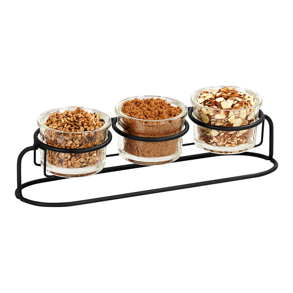 A group of glass containers with black rings filled with different types of food on a metal stand.