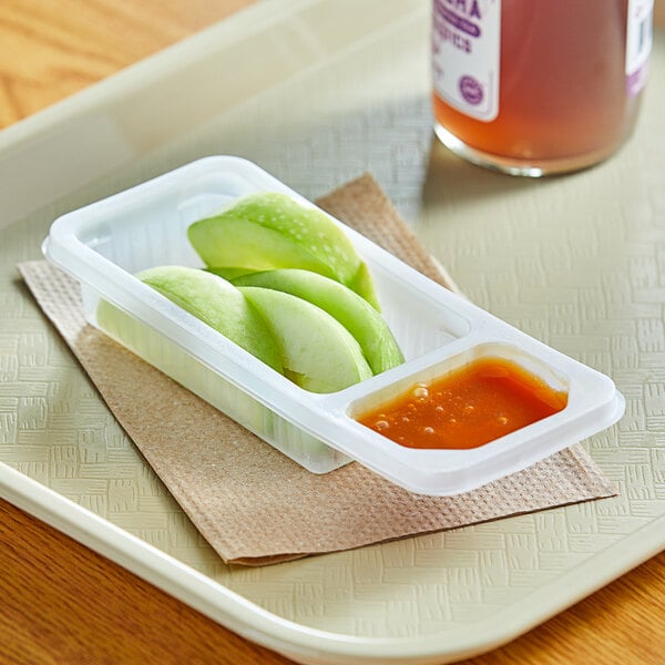 A tray with two plastic containers of sliced apples and caramel sauce.