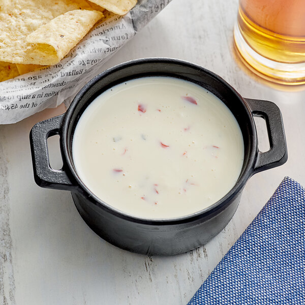 A bowl of Land O Lakes Queso Bravo white cheese dip next to tortilla chips.