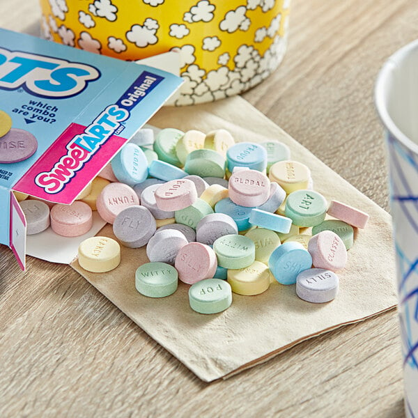 A pile of SweeTarts candy on a napkin next to a box of SweeTarts.