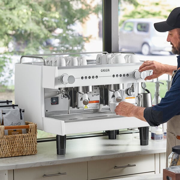 A man using a white Gaggia Vetro espresso machine.