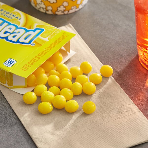 A yellow Lemonhead candy box on a table.