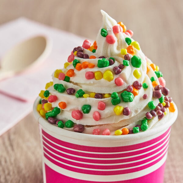 A cup of ice cream with Nerds candy on top and colorful sprinkles.