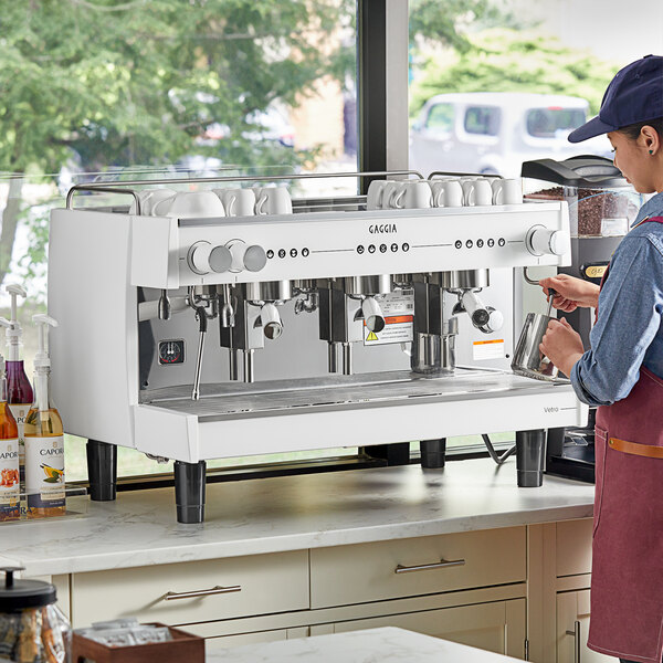 A man in a black shirt using a white Gaggia Vetro espresso machine.