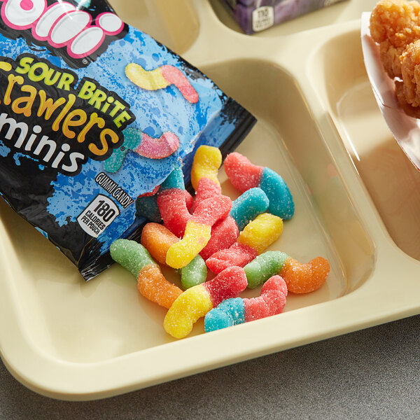 A table with a tray of Trolli Mini Sour Brite Crawlers bags.