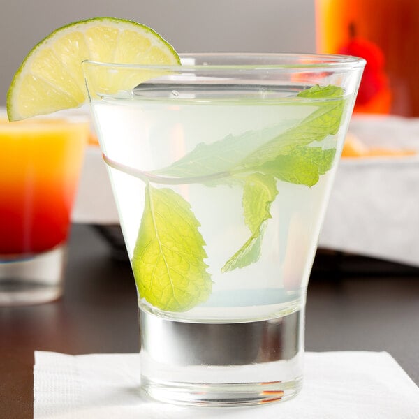 A Libbey customizable rocks glass with water and leaves in it, and a lime wedge.