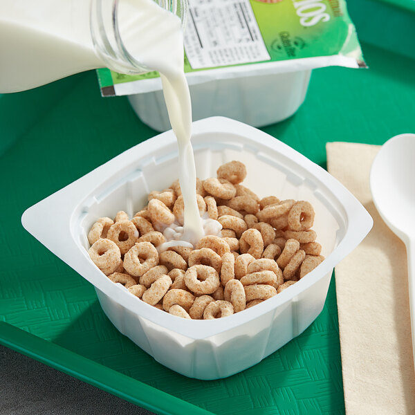 A bowl of Apple Cinnamon Cheerios with milk being poured into it.