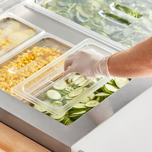 A gloved hand places a Choice clear plastic lid on a food container.