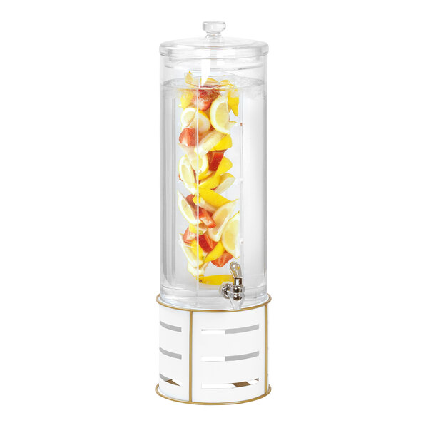 A Cal-Mil round plastic beverage dispenser with fruit inside on a white and gold metal base.