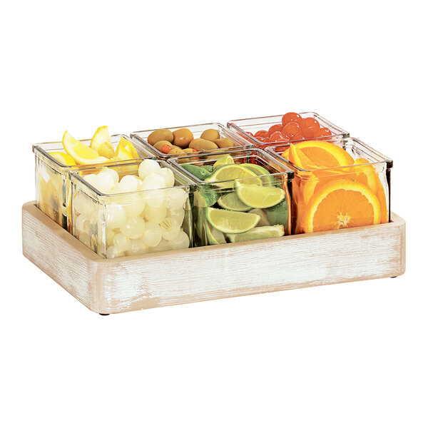 A white-washed wood Cal-Mil condiment organizer tray with glass containers of fruit.