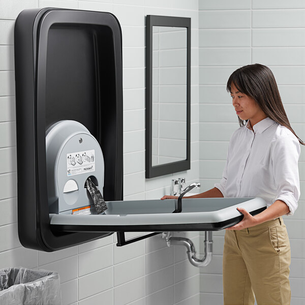 A woman holding a Koala Kare stainless steel baby changing station.