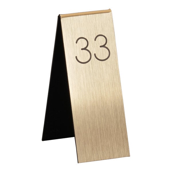 A gold metal Cal-Mil table number tent with black numbers.