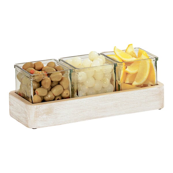 A Cal-Mil white-washed wood condiment organizer with 3 glass containers holding lemons and olives.