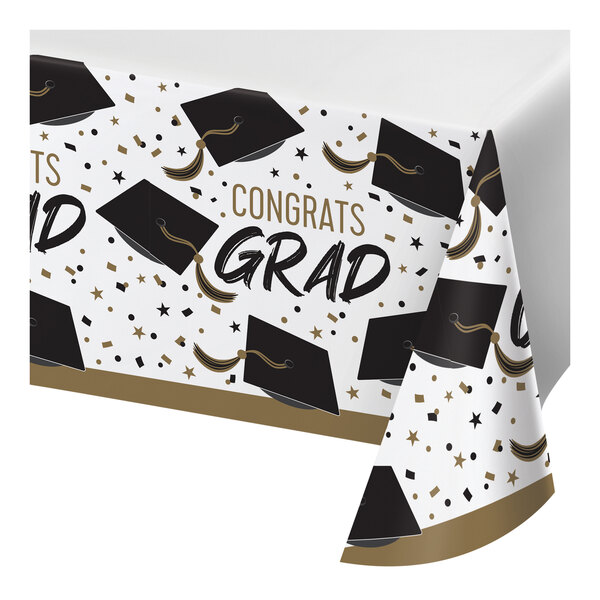 A white paper tablecloth with black and gold graduation caps and stars on it.