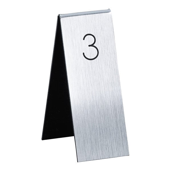 A silver metal Cal-Mil table number with the number three on it.