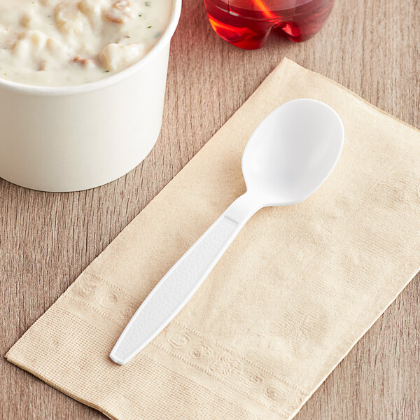 A Visions white heavy weight plastic soup spoon on a napkin.