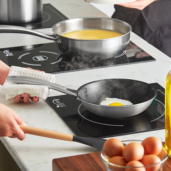 A woman cooking eggs in a Vigor SS3 stainless steel non-stick frying pan.