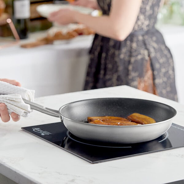 A woman using a Vigor SS3 Series stainless steel non-stick fry pan to cook food.