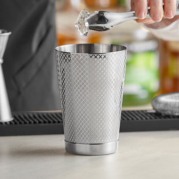 A person using a Barfly stainless steel cocktail shaker to pour a drink.