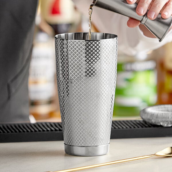 A bartender pouring a drink into a Barfly stainless steel cocktail shaker.