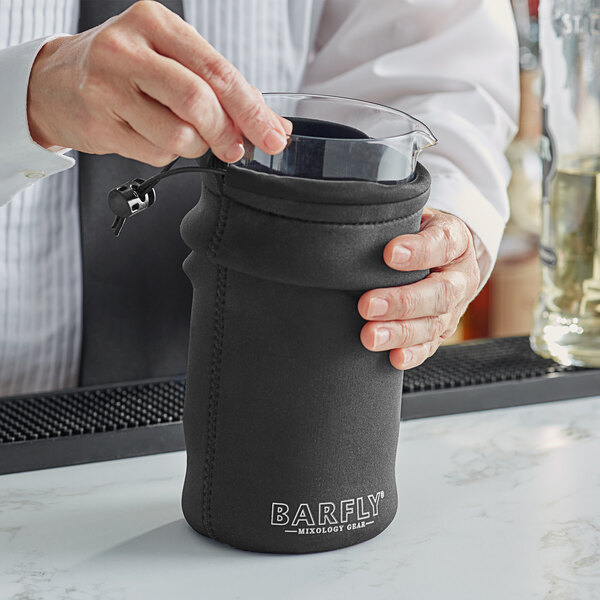 A person using a Barfly gray protective sleeve to hold a glass container.